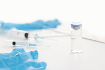 Medicine bottle, blue rubber gloves, syringes and papers on light background. Coronavirus vaccine development. Medical equipment, 2019-nCoV liquid drug, virus antidote. Health care concept.