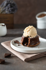 Warm Chocolate Lava Cake with Bite Taken Out of Molten Center and scoop of vanilla ice cream on dark background. Restaurant, bakery, confectionery menu, recipe
