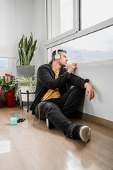 Guy quarantine at home using technology and looking out the window. Coronavirus concept COVID-19