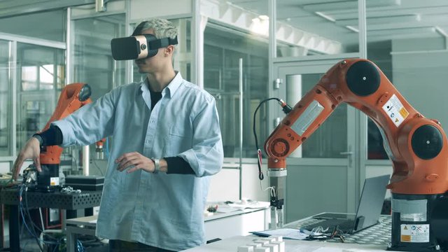 Engineer in VR-glasses is manipulating a bionic device. High school students studying robotics technologies at university lab.