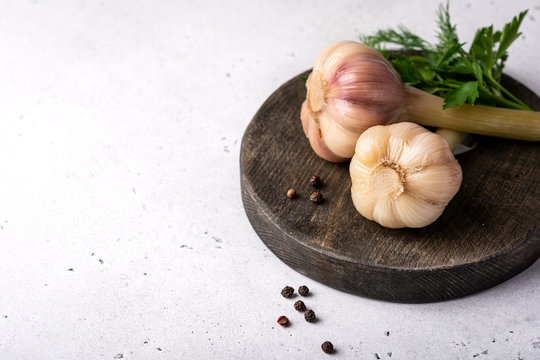 pickled garlic on a wooden cutting board on a light background, copy space