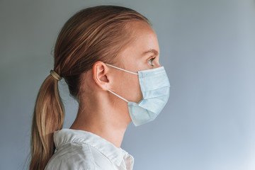 A girl in a medical mask on a gray background. copy space