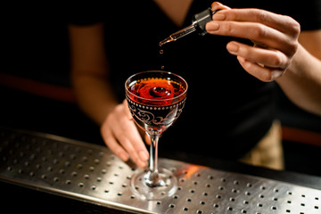 Close-up of barman's hand adding ingredient to cocktail using dropper