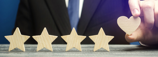 A man points to a heart instead of a fifth star. Loyalty and customer choice. The evaluation of...