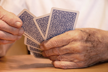 Alter Mensch hält Kartenspiel in Hand und zieht eine Karte