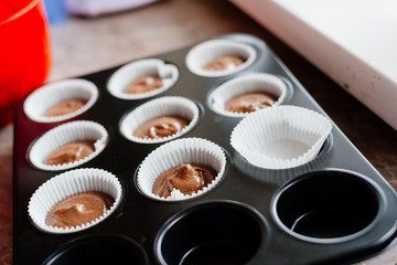 Chocolate cupcakes. Homemade chocolate muffins. The process of making homemade chocolate cupcakes with whipped cream and decorated with chocolate and raspberry pieces.