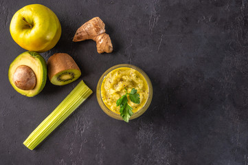 Freshly made green smoothie made of vegetables, fruits, herbs and greens on a dark background. Copy space