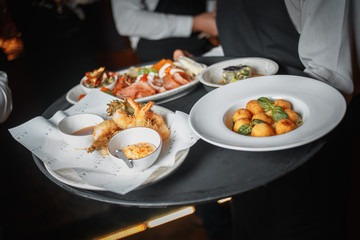cropped shot of waiter holding tray with various food