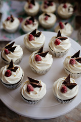 Chocolate cupcakes. Homemade chocolate muffins. The process of making homemade chocolate cupcakes with whipped cream and decorated with chocolate and raspberry pieces.