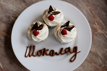 Chocolate cupcakes. Homemade chocolate muffins. The process of making homemade chocolate cupcakes with whipped cream and decorated with chocolate and raspberry pieces.