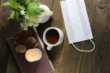 cup of tea or coffee and medical protective mask. on wooden table. Virus concept. Quarantine at home.