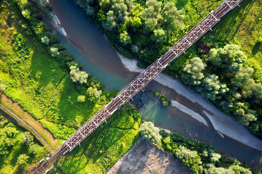 Steel railroad bridge above a river with blue water. Aerial drone view. Landscape photography