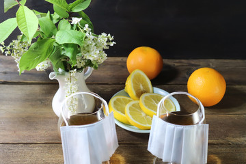 Glass goblets with alcohol. Medical protective mask. Citrus fruits. On a wooden table. Virus concept. Quarantine at home.