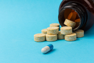 Pills isolated on blue background. Medical drug capsule. Concept of coronavirus
