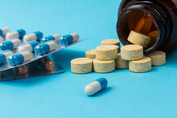 Pills isolated on blue background. Medical drug capsule. Concept of coronavirus
