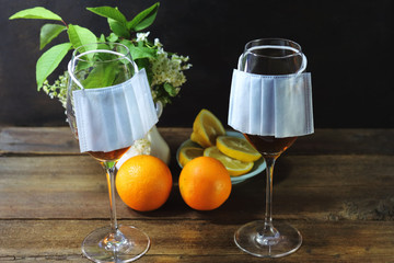 Glass goblets with alcohol. Medical protective mask. Citrus fruits. On a wooden table. Virus concept. Quarantine at home.