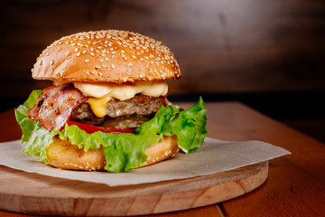 classic burger with juicy beef patty, cheese and bacon on a dark background