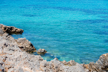 Fototapeta na wymiar Closeup of vibrant blue waters and rocky coastline at Agia Dynami beach.