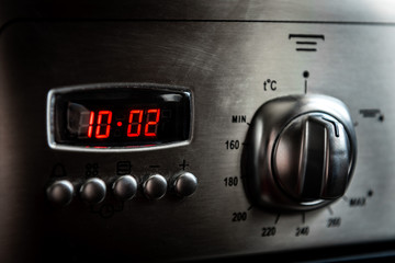 Control buttons and time display of modern kitchen electrical oven. 