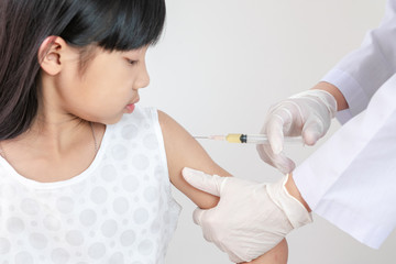 The doctor is injecting medicine for treatment or a vaccine to prevent corona virus or Covid 19 in the arms of an Asian girl.