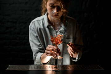 Female bartender holds glass with splashing drink in her hand.