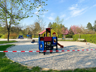 Children's playground in the park is closed and wrapped in alarm caution tape for global coronavirus quarantine. No children on playgrounds in Europe. Prevention of coronavirus COVID-19.