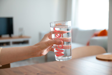 young beautiful lady drinking water in clean clear glass standing on table healthy