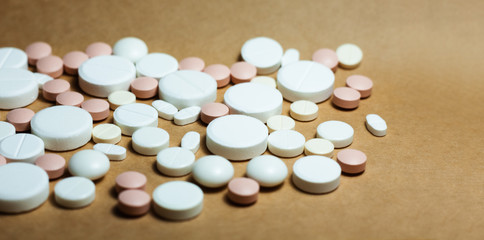 Obraz na płótnie Canvas Heap of white pills, tablets, capsules on yellow orange background. Drug prescription for treatment medication health care concept wth copy space.