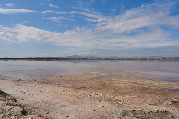 Beautiful panoramic view of a mountain from the shore of the salty lake Larnaca with blue sky and small clouds, reflections in the water, Larnaca, island Cyprus, deserted landscape
