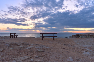 Fototapeta na wymiar beautiful sunset with spectacular colours, a fantastic sky and an unobstructed view of the sea from a bench at the sea caves of Ayia Napa in the Cape Greco National Forest Park in Cyprus 