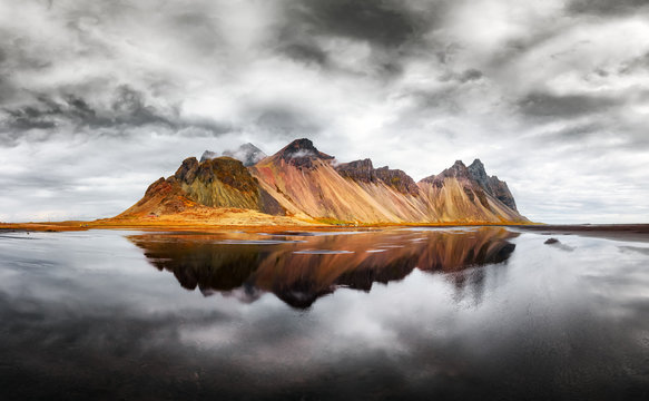 Incredible landscape of the famous Stokksnes mountains on Vestrahorn cape. Reflection in the clear water on the epic skies background, Iceland