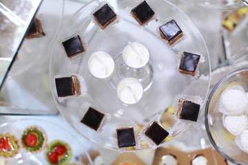 Close up of tray with lot delicious diversity pastry cakes tartlets and macaroon in a row. Fresh, multicoloured, colourful, green, yellow, white and pink sweet berry desserts, beautifully decorated