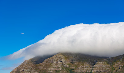 Devils Peak on Table Mountain on a cloudy day with a Airplane flying by