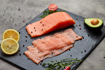 Fresh sliced salmon fillet with arugula, avocado and lemon on slate plate. Wild atlantic fish