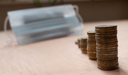 Piles of coins of different heights and a medical mask