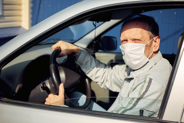 a man driving a car puts on a medical mask during an epidemic, a taxi driver in a mask, protection...