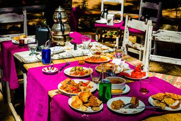 National Turkish style in the interior of an open-air restaurant. Colored chairs, tables and textiles. National dishes and modern carbonated drinks on the table.