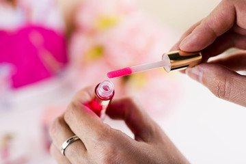 Smear of pink lip gloss and brush on a white background. Sample of liquid lipstick and stick isolate. Texture female beauty make-up product, brush stroke.