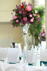 table setting at white wedding reception, floral composition, candles and cones, lights on the background