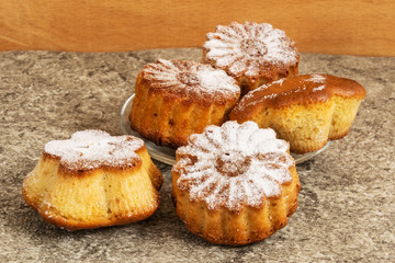 Homemade muffins sprinkled with powdered sugar on a gray background.