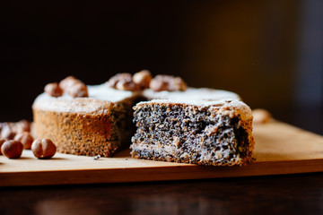 Biscuit with poppy seeds and nuts dusted with icing sugar. From a homemade cake cut a piece. Homemade sponge cake with poppy seeds and nuts, next to it is a cup with tea. Steam rises above the cup.