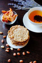 Oatmeal cookies and tea. A stack of oatmeal cookies on the table, next to a cup of tea, peanuts, dried apples and sprigs of lavender