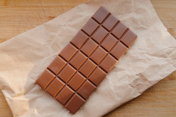 A bar of milk chocolate. Homemade milk chocolate with almonds and dried strawberries. Pieces of milk chocolate. Unlabeled milk chocolate bar