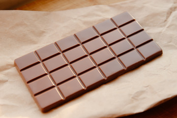 A bar of milk chocolate. Homemade milk chocolate with almonds and dried strawberries. Pieces of milk chocolate. Unlabeled milk chocolate bar