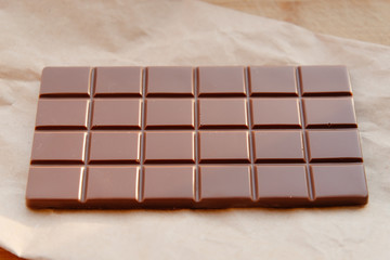A bar of milk chocolate. Homemade milk chocolate with almonds and dried strawberries. Pieces of milk chocolate. Unlabeled milk chocolate bar