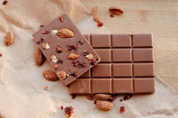 A bar of milk chocolate. Homemade milk chocolate with almonds and dried strawberries. Pieces of milk chocolate. Unlabeled milk chocolate bar