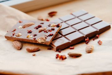 A bar of milk chocolate. Homemade milk chocolate with almonds and dried strawberries. Pieces of milk chocolate. Unlabeled milk chocolate bar