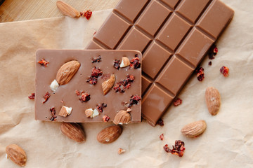 A bar of milk chocolate. Homemade milk chocolate with almonds and dried strawberries. Pieces of milk chocolate. Unlabeled milk chocolate bar