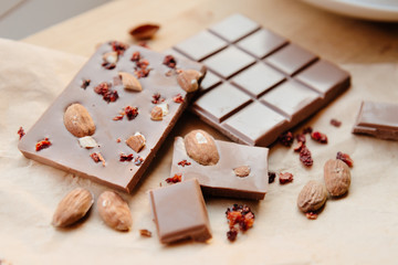 A bar of milk chocolate. Homemade milk chocolate with almonds and dried strawberries. Pieces of milk chocolate. Unlabeled milk chocolate bar