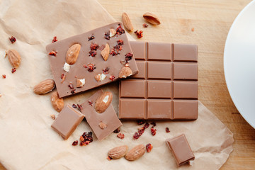 A bar of milk chocolate. Homemade milk chocolate with almonds and dried strawberries. Pieces of milk chocolate. Unlabeled milk chocolate bar